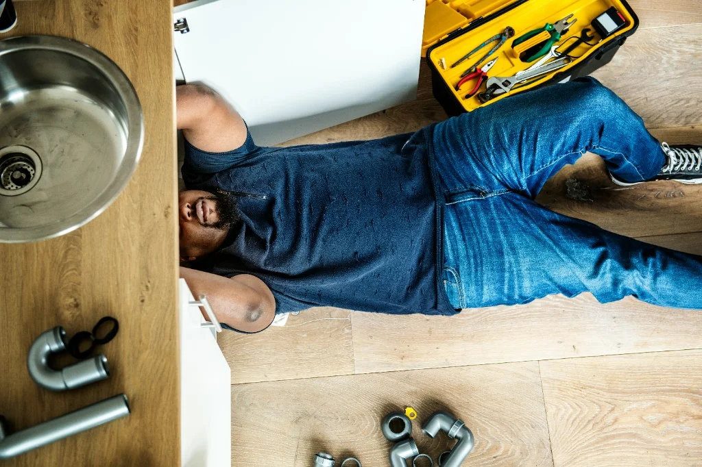 Certified plumber working under a kitchen sink