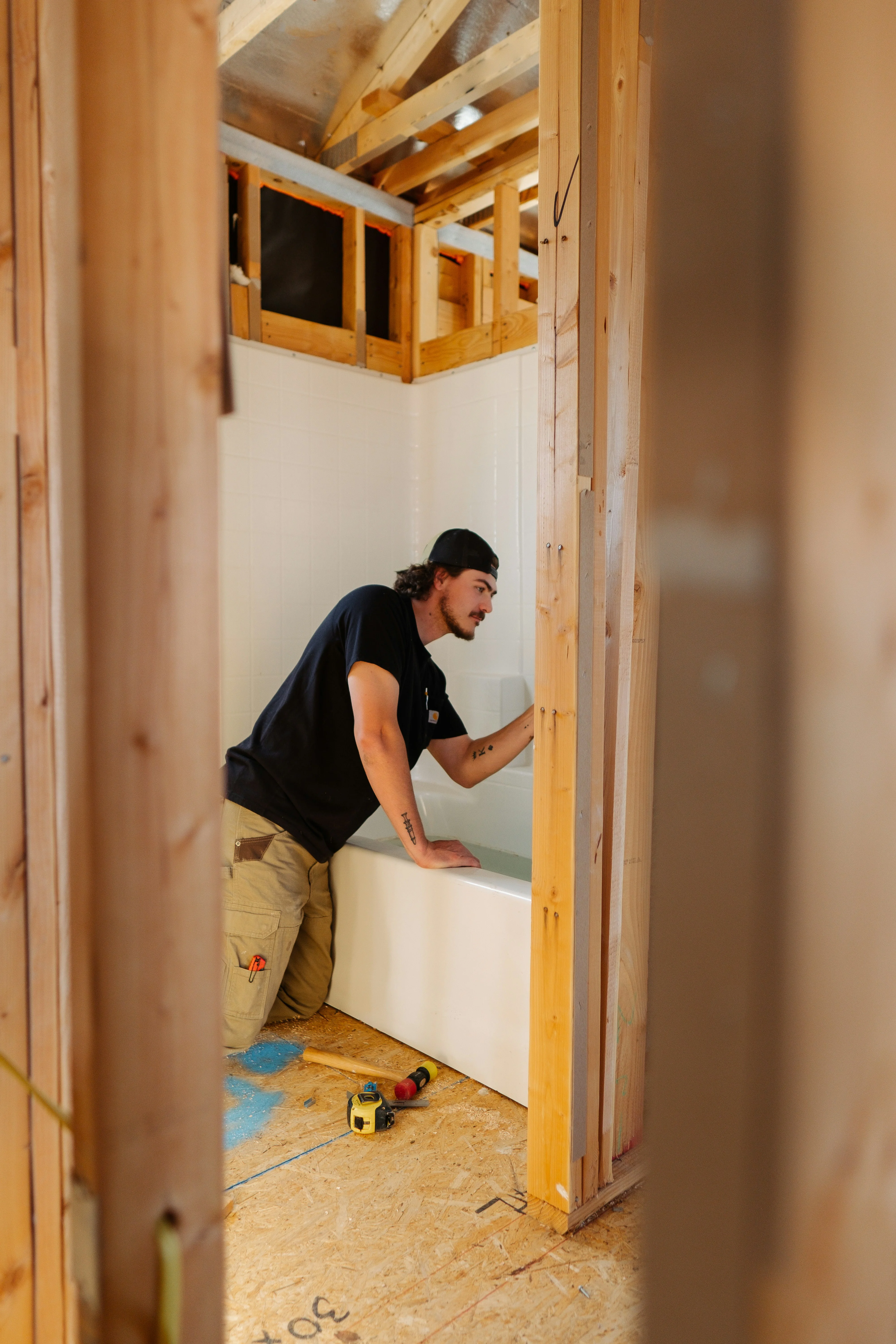 Plumber installing a bathtub in a bathroom under construction