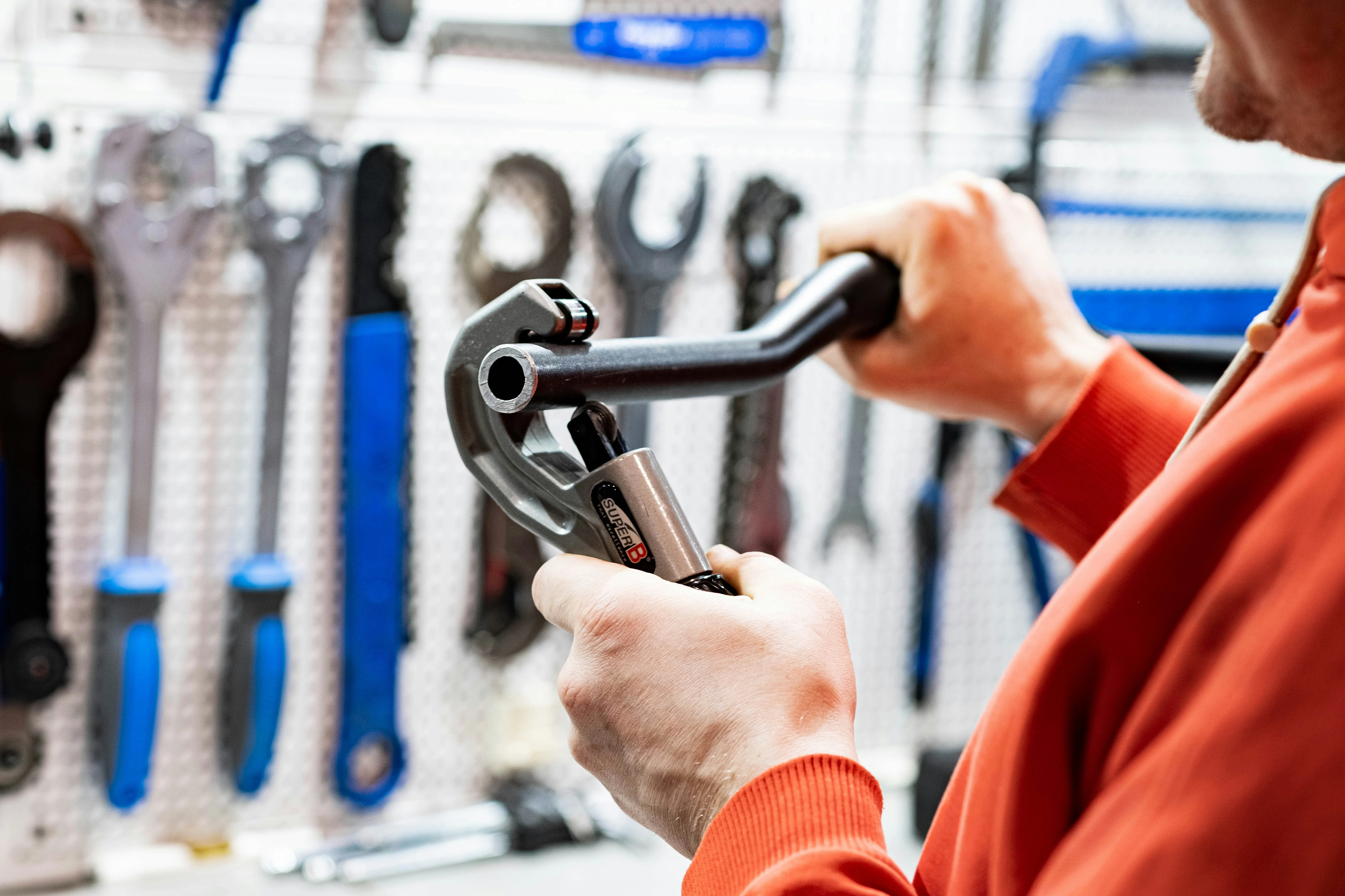 Plumber cutting a pipe with a professional pipe cutter in a workshop